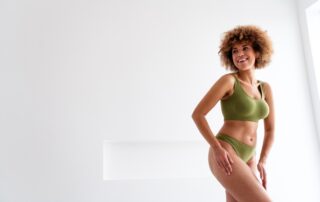 A woman smiling while posing in a green matching underwear set.