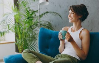 A woman drinking coffee on her couch.