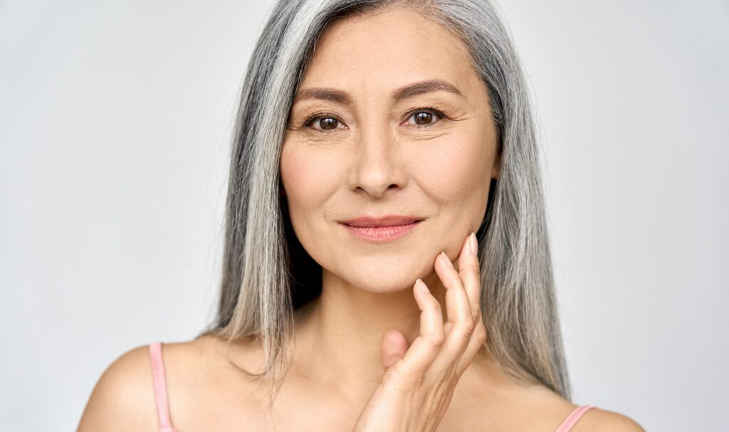 Older woman with grey hair, admiring face.