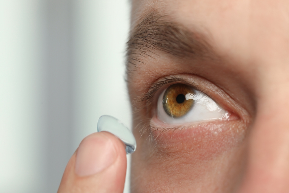 man with brown eyes putting in contact lens