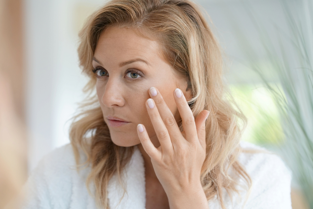 A woman examining the wrinkles on her face.