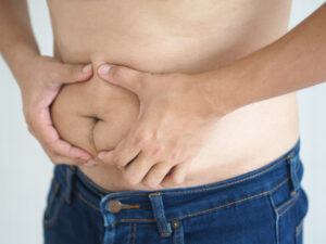 A man grabbing his excess stomach weight.
