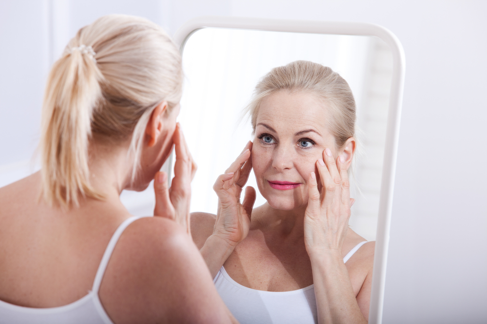 A woman looking at her face in the mirror